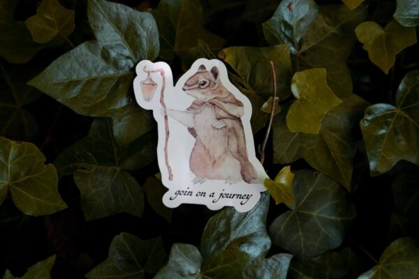 Squirrel Sticker, he is holding a lamp and underneath him is text saying "goin on a journey"